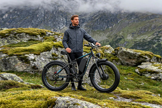 E-BYCCO EB7 Pro fat-tire e-bike with full suspension, parked on mossy mountain terrain with a man standing beside it.